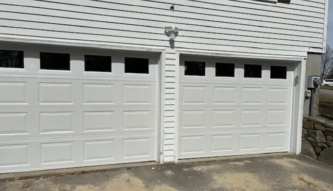 Two white garage doors with row of windows at the top